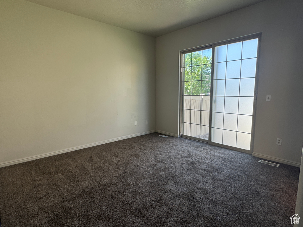 Unfurnished room with dark colored carpet and baseboards