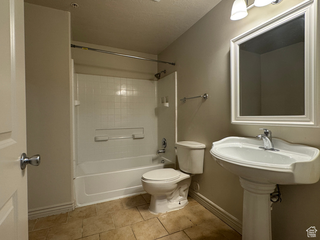 Full bath featuring toilet, baseboards, shower / bathtub combination, a textured ceiling, and tile patterned floors