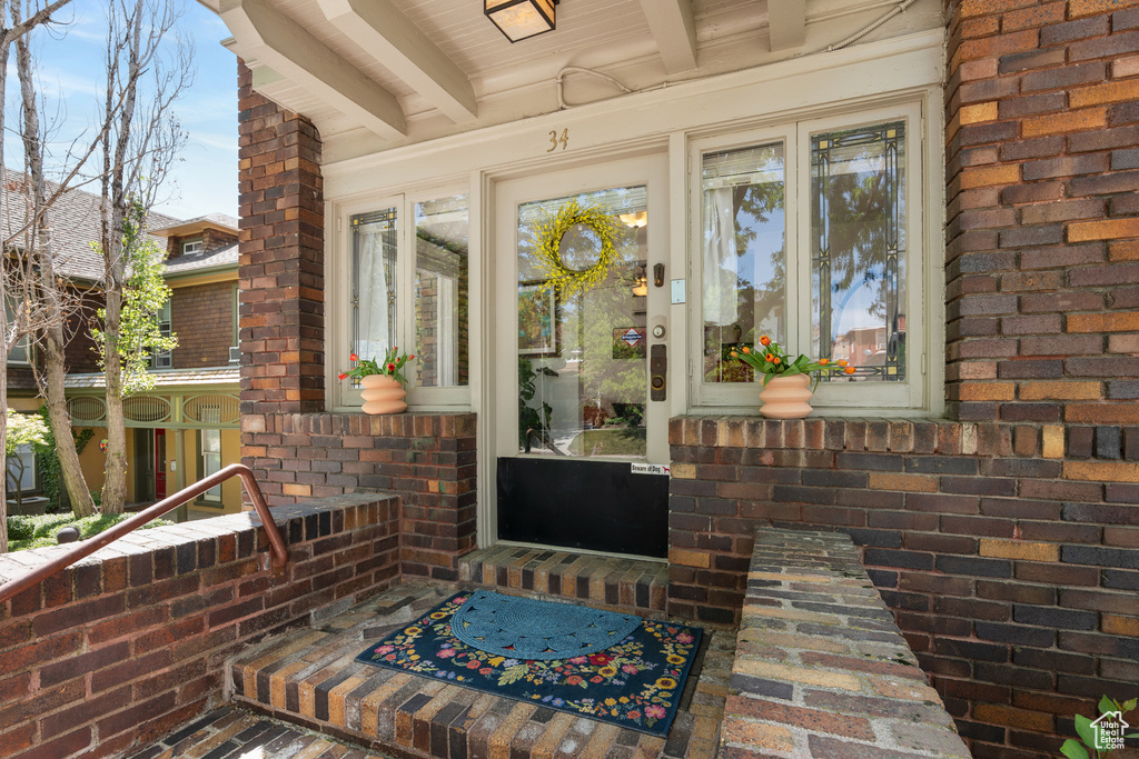 Doorway to property featuring brick siding and a porch