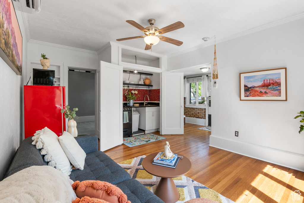 Living area with a ceiling fan, light wood finished floors, crown molding, and baseboards