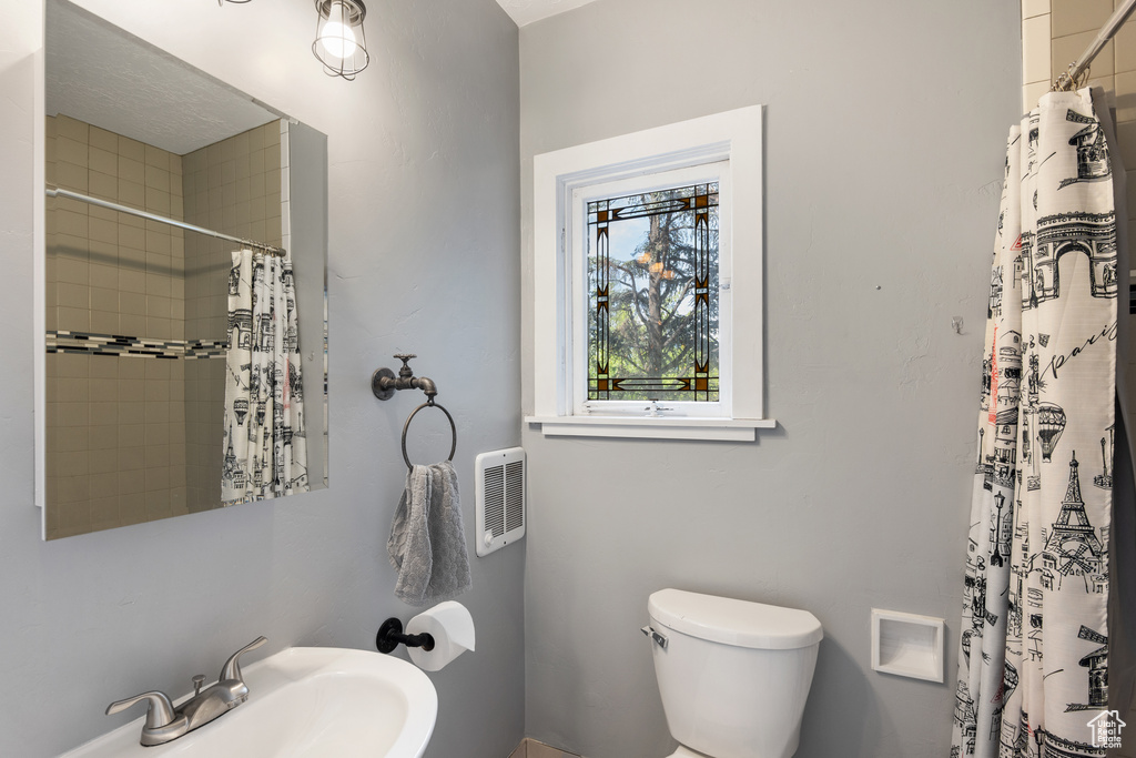 Bathroom featuring a sink, toilet, and a shower with curtain