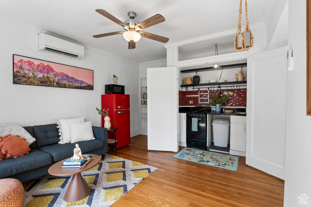 Living area with an AC wall unit, ornamental molding, wood finished floors, and a ceiling fan