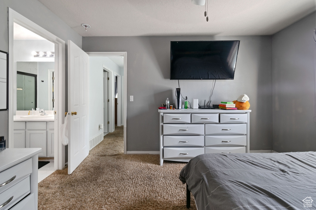 Carpeted bedroom featuring a sink, connected bathroom, and baseboards