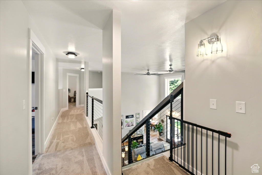 Hall featuring an upstairs landing, light carpet, and baseboards