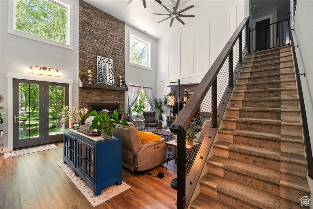 Stairway with a fireplace, a towering ceiling, wood finished floors, and a ceiling fan