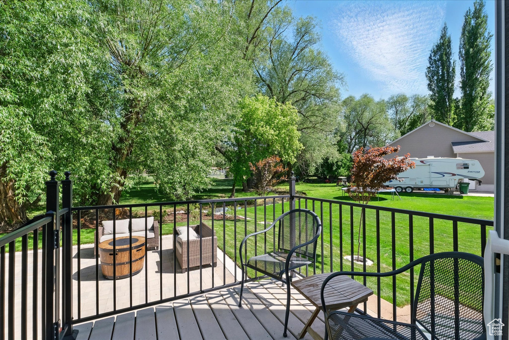 Wooden deck with an outdoor living space with a fire pit and a yard