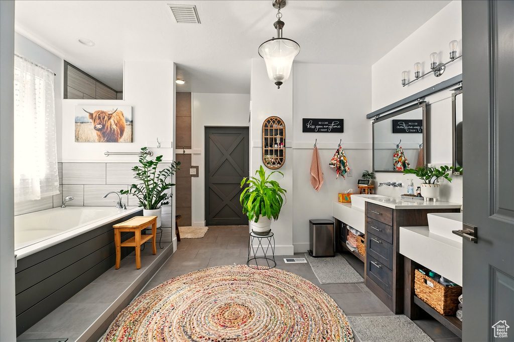 Bathroom featuring a garden tub, vanity, and tile patterned floors