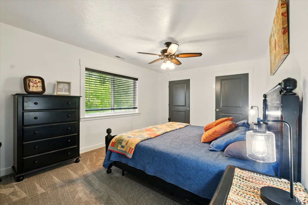 Bedroom with dark colored carpet, ceiling fan, and baseboards