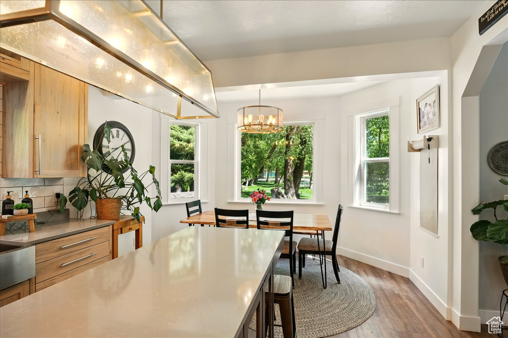 Kitchen featuring wood finished floors, a chandelier, baseboards, light countertops, and a kitchen breakfast bar