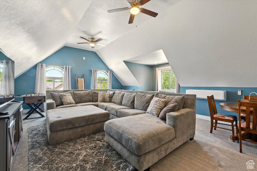 Carpeted living room with ceiling fan, lofted ceiling, a textured ceiling, and baseboards