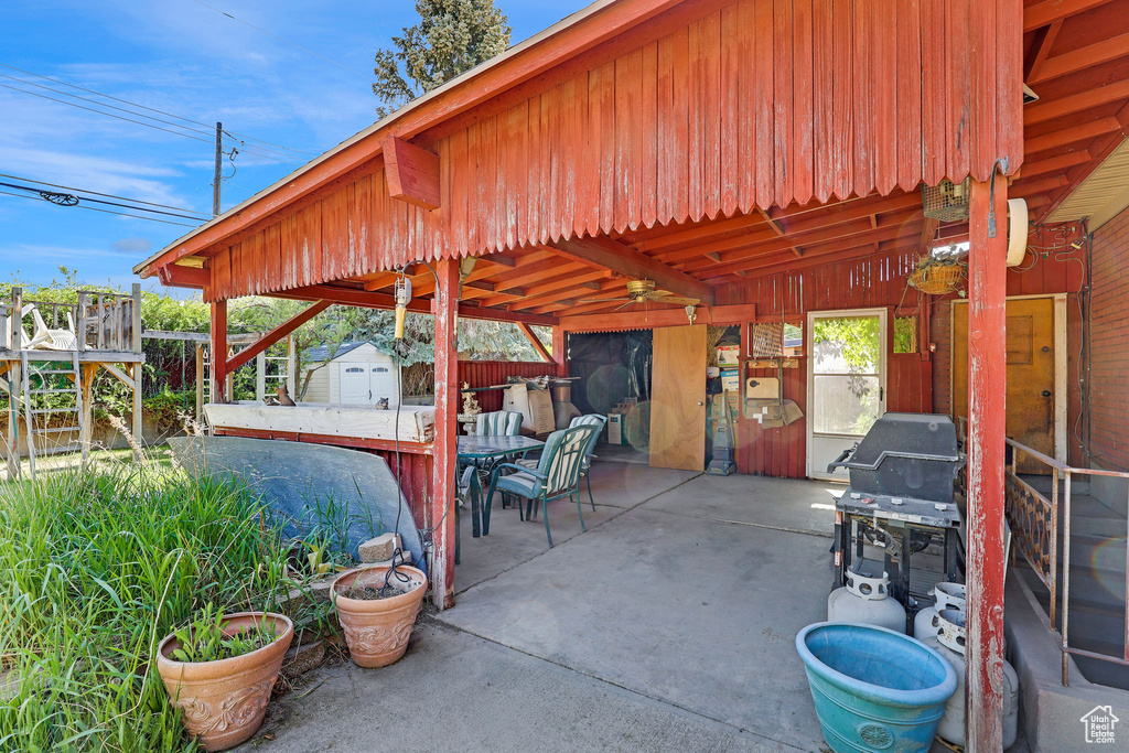 View of patio with a storage unit, an outbuilding, outdoor dining area, and fence