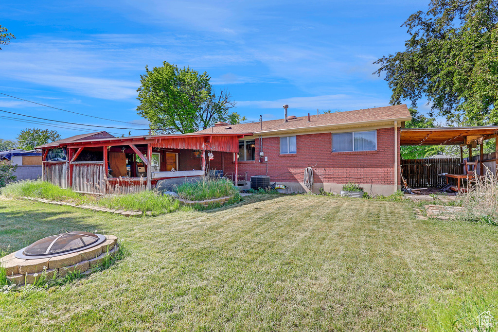 Rear view of house with an outdoor fire pit, brick siding, and central AC unit