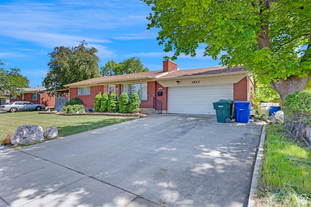 Ranch-style house with brick siding, an attached garage, a chimney, concrete driveway, and a front yard