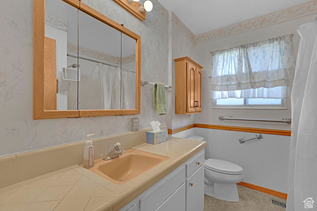 Full bathroom featuring toilet, vanity, a shower with curtain, and wallpapered walls