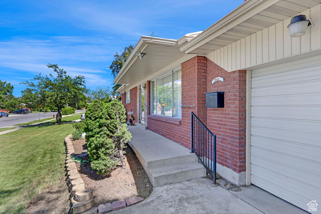 Entrance to property with brick siding and a lawn