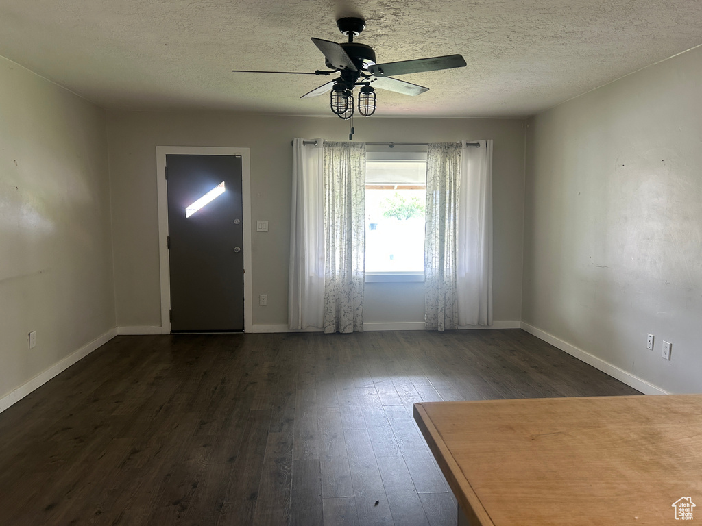 Entrance foyer featuring dark wood-type flooring, ceiling fan, baseboards, and a textured ceiling