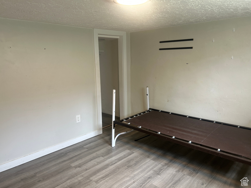 Empty room with wood finished floors, a textured ceiling, and baseboards