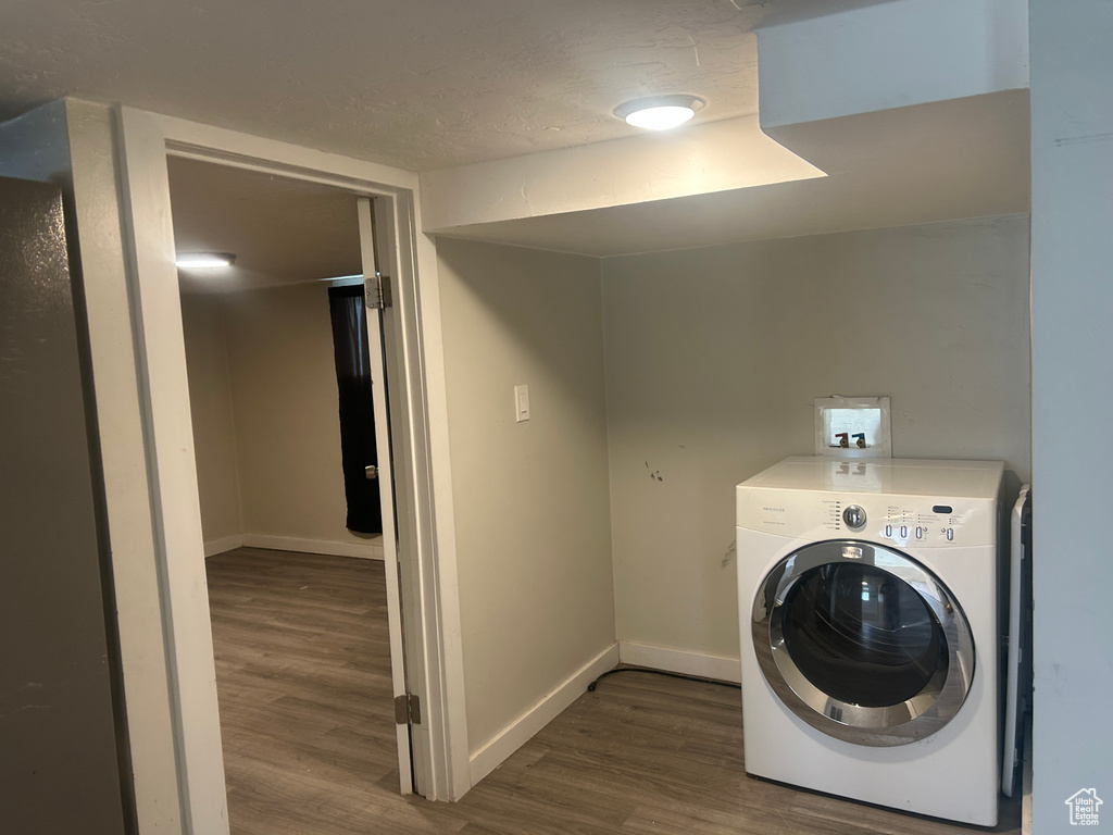 Clothes washing area featuring washer / dryer, wood finished floors, and baseboards