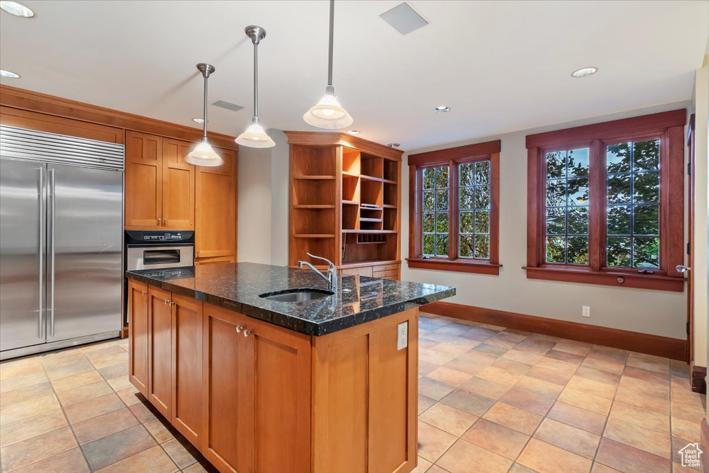 Kitchen with stainless steel appliances, a sink, baseboards, recessed lighting, and dark stone countertops