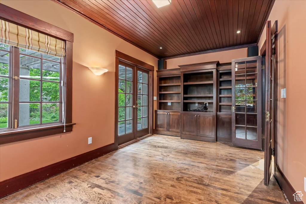 Unfurnished office featuring french doors, wood ceiling, plenty of natural light, wood finished floors, and baseboards