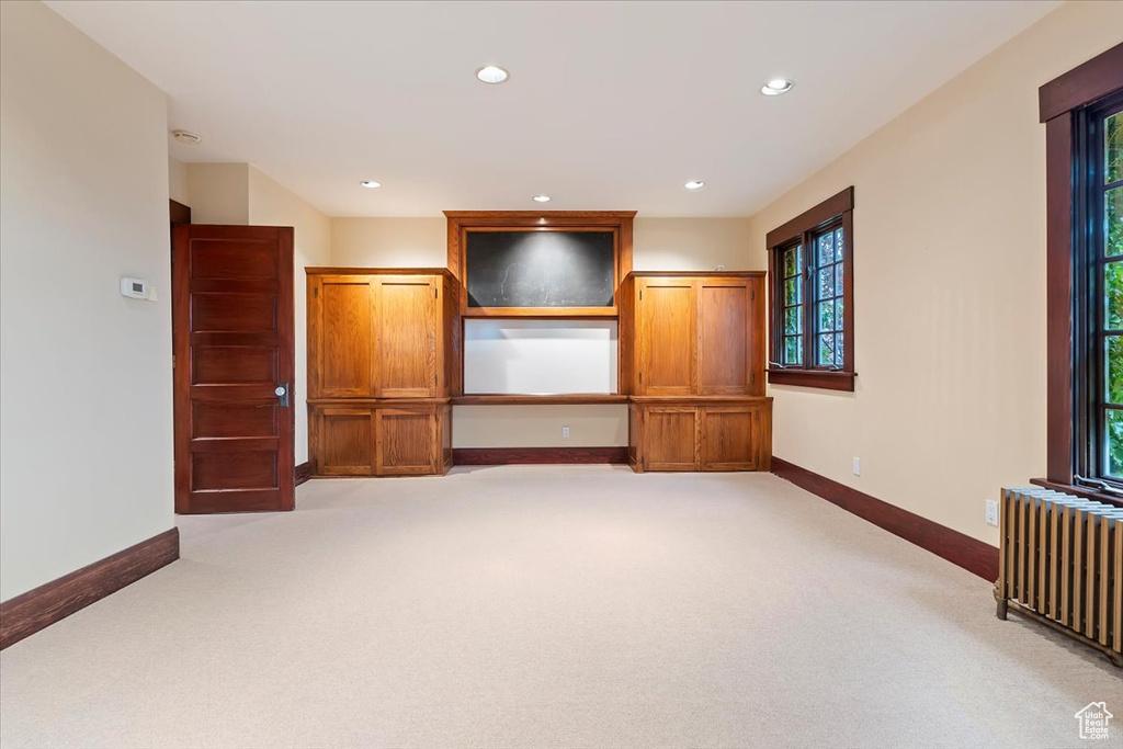Spare room featuring radiator heating unit, light colored carpet, baseboards, and recessed lighting