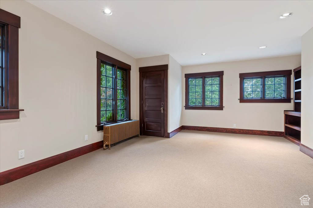Carpeted empty room with radiator, baseboards, and recessed lighting