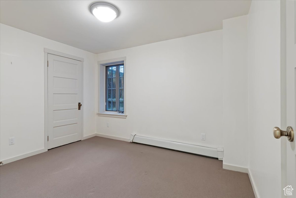Empty room featuring a baseboard radiator, carpet flooring, and baseboards