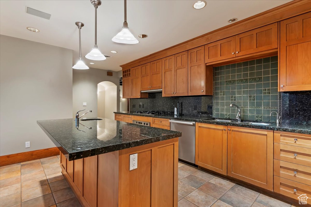 Kitchen with stainless steel dishwasher, a sink, arched walkways, decorative backsplash, and recessed lighting