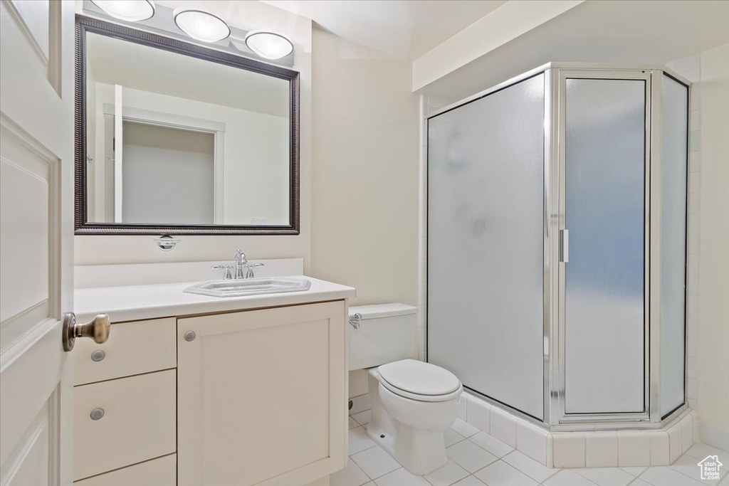 Bathroom with toilet, tile patterned flooring, a stall shower, and vanity