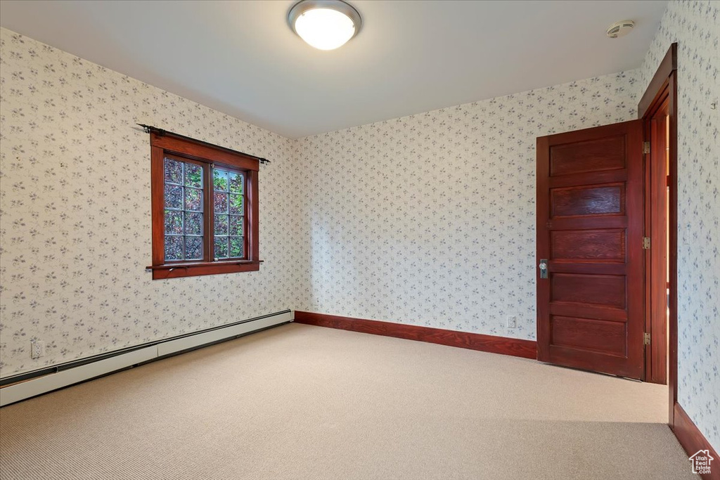 Carpeted spare room featuring a baseboard heating unit, a smoke detector, and wallpapered walls