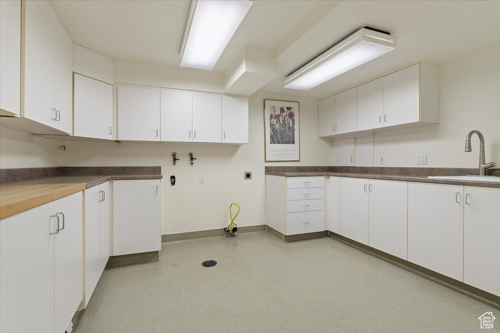Kitchen with a sink, white cabinets, and baseboards