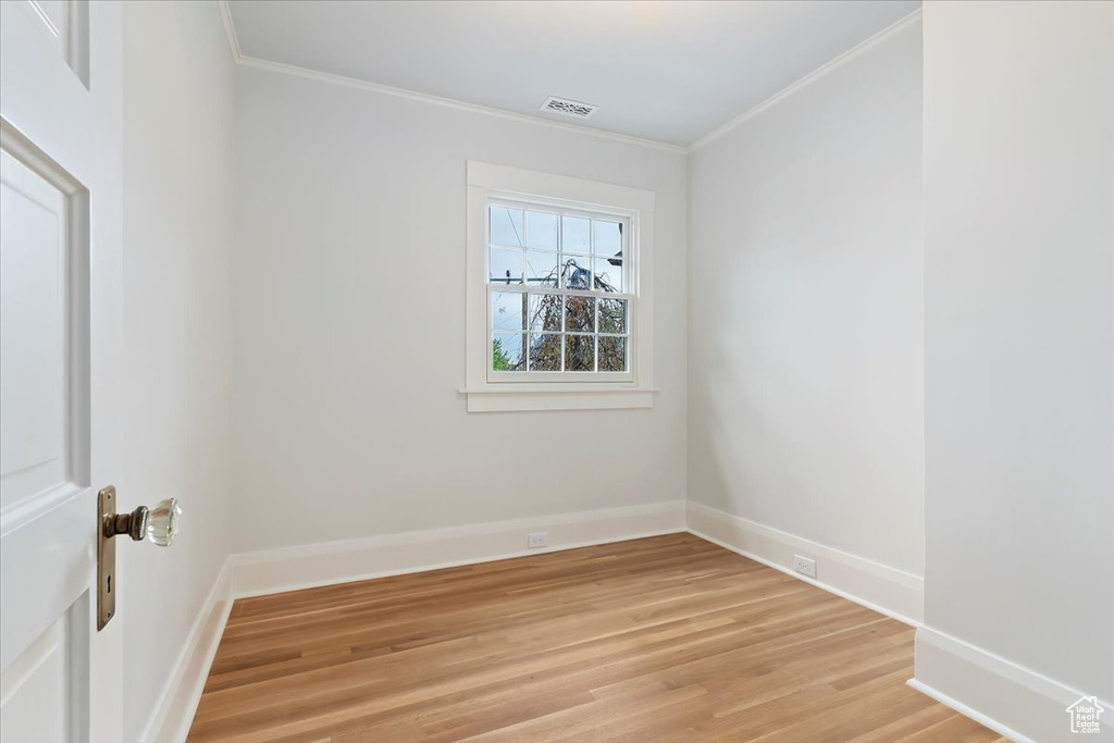 Unfurnished room featuring ornamental molding, light wood finished floors, and baseboards
