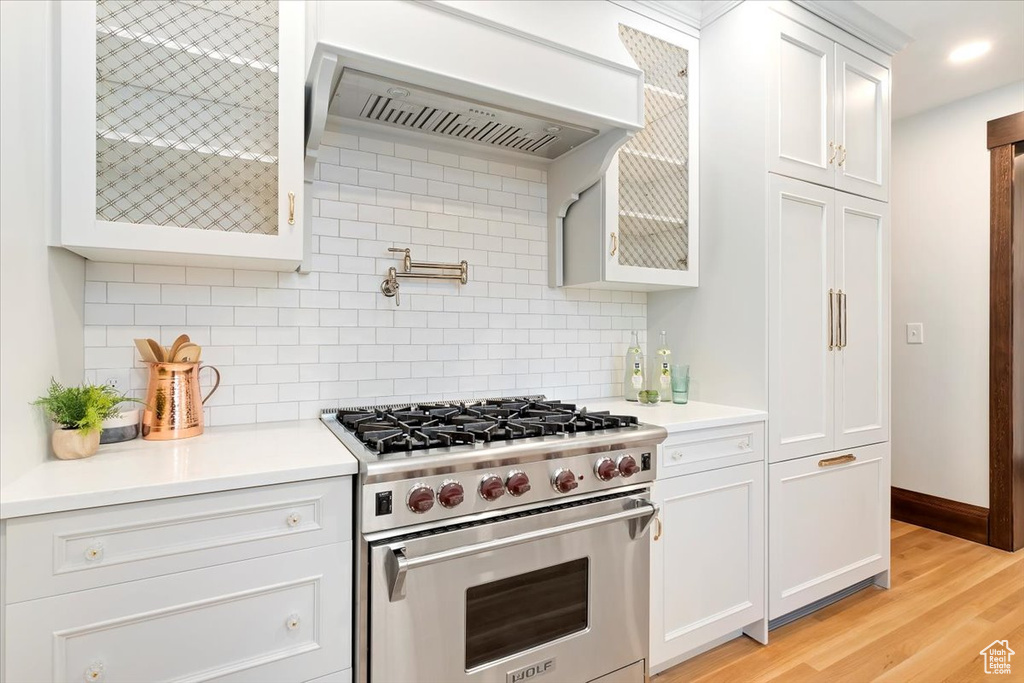 Kitchen featuring premium stove, ventilation hood, light countertops, backsplash, and recessed lighting