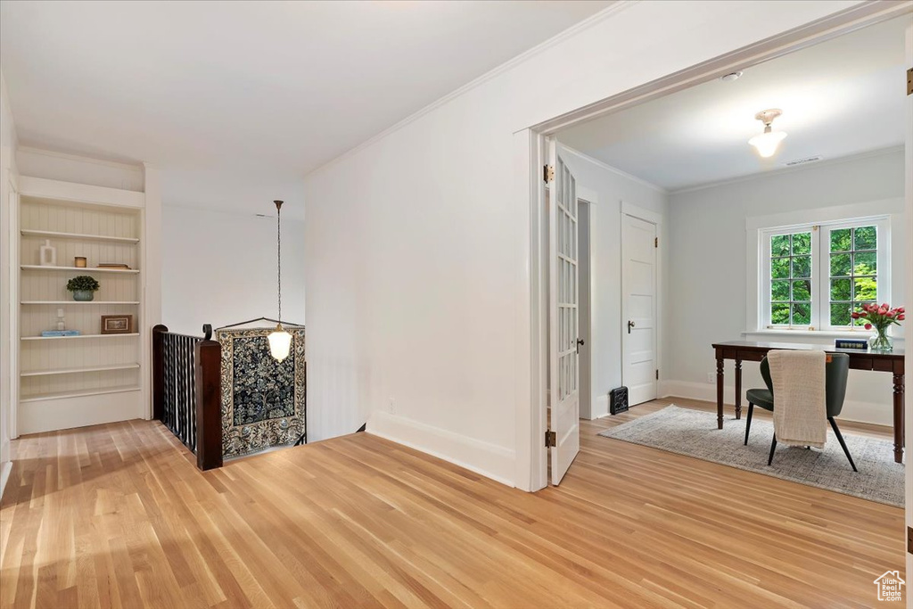 Corridor featuring light wood-type flooring, crown molding, an office area, baseboards, and built in shelves