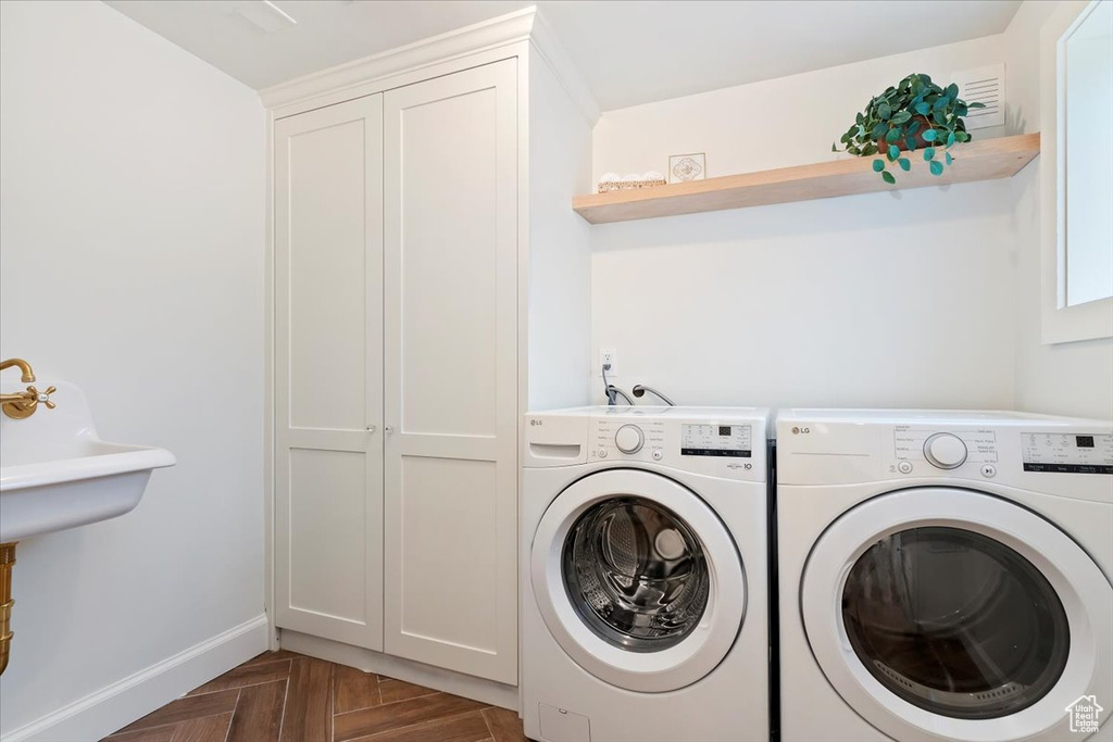 Clothes washing area with washing machine and clothes dryer, cabinet space, and baseboards