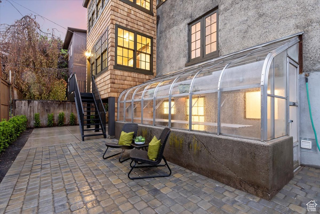 View of patio featuring stairs, fence, and a sunroom