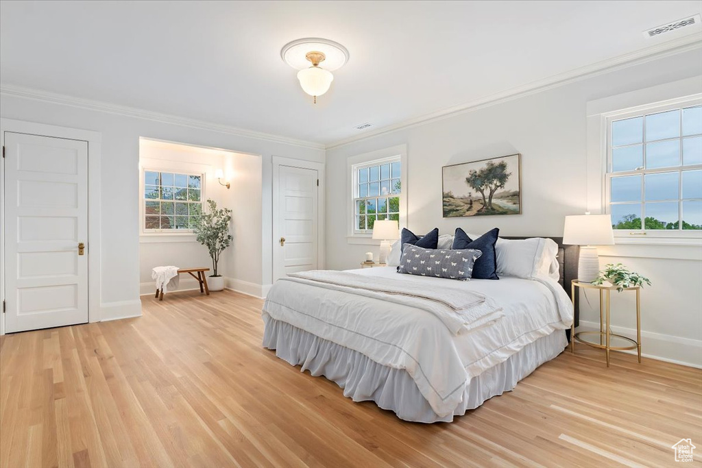 Bedroom with crown molding, light wood-style floors, and baseboards
