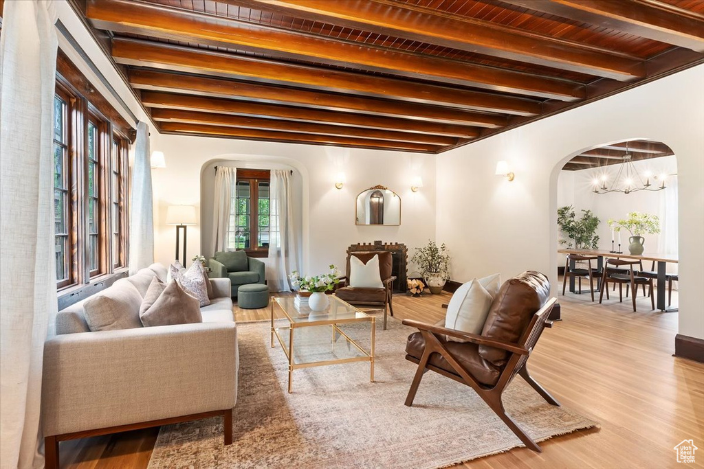 Living room with arched walkways, beamed ceiling, a chandelier, wood finished floors, and wood ceiling
