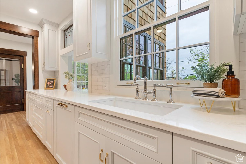 Bar area with a sink, light wood finished floors, tasteful backsplash, and recessed lighting