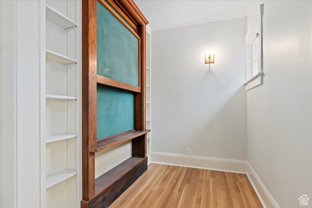 Hall featuring wood finished floors, baseboards, and crown molding