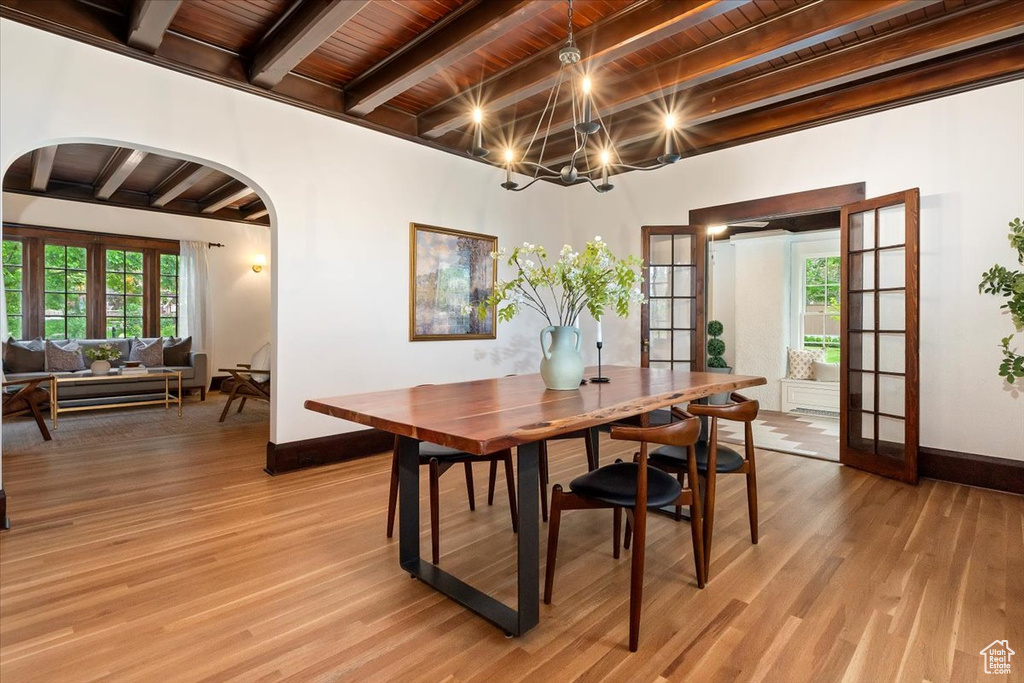 Dining room featuring french doors, beam ceiling, light wood-style flooring, baseboards, and arched walkways