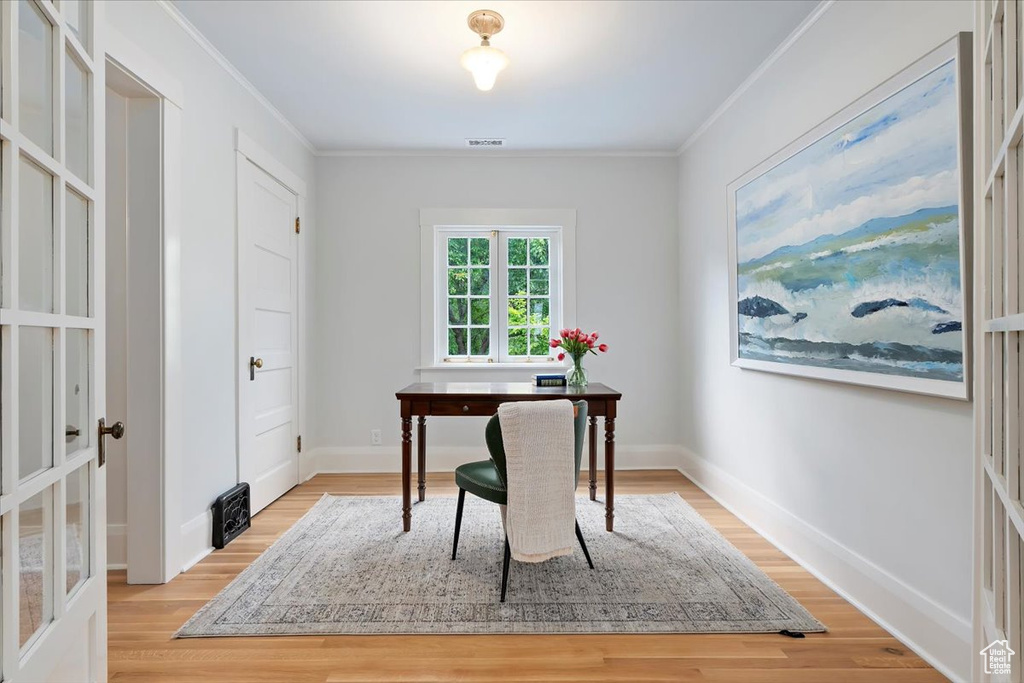 Home office featuring ornamental molding, light wood finished floors, and baseboards