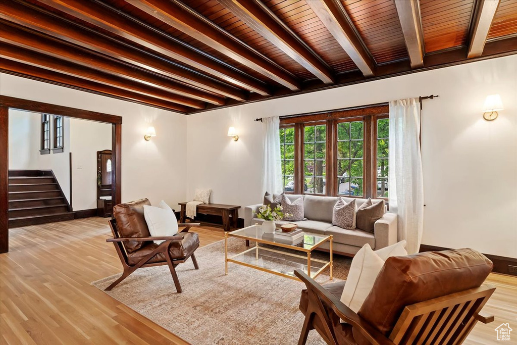 Living room featuring beamed ceiling, stairs, light wood finished floors, and wood ceiling