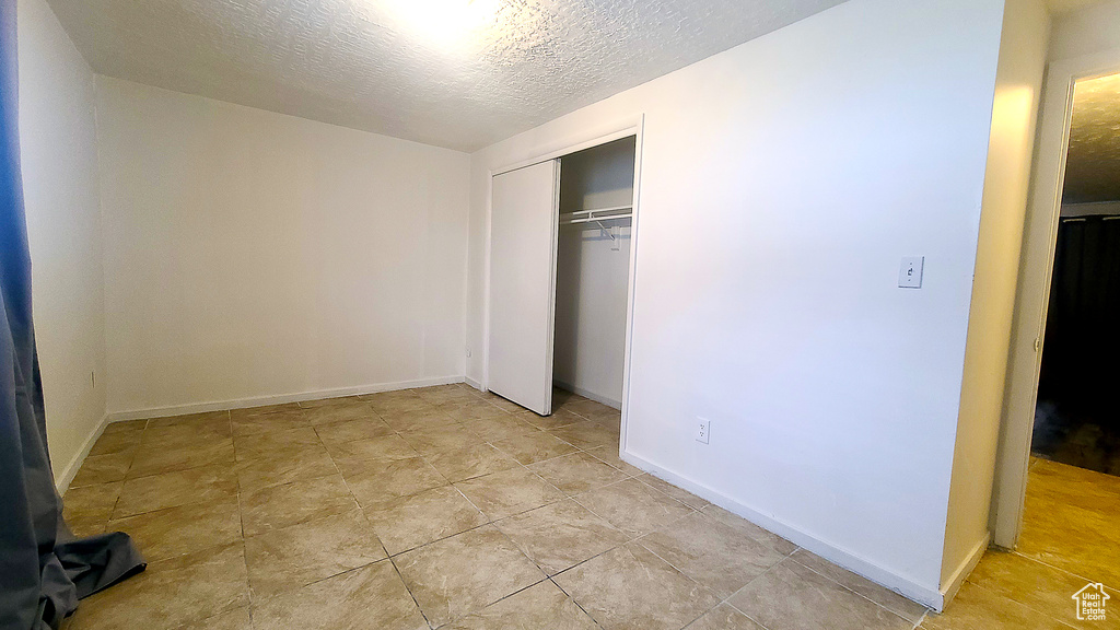 Unfurnished bedroom featuring a closet, a textured ceiling, and baseboards