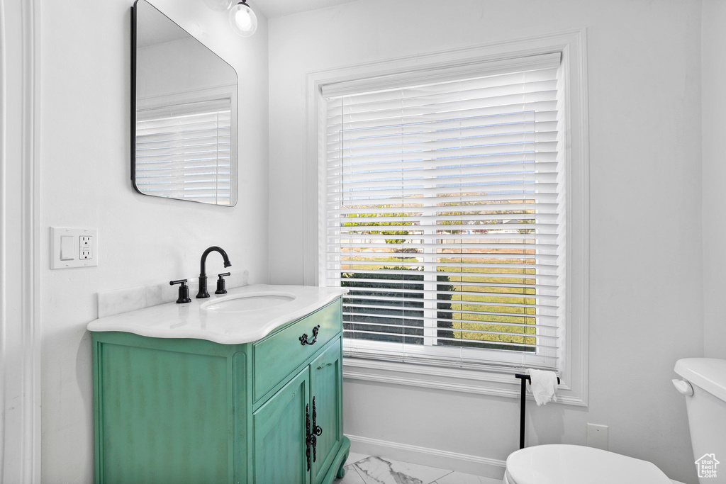 Half bath with marble look tiles, toilet, and vanity