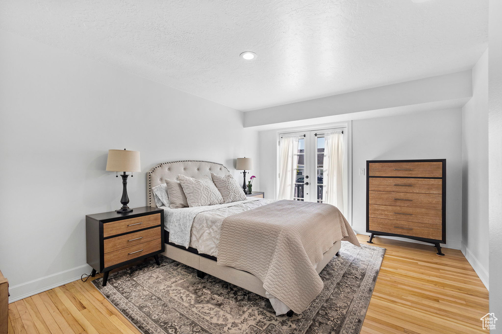 Bedroom with access to outside, light wood-style flooring, baseboards, a textured ceiling, and recessed lighting
