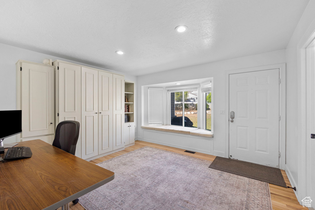 Unfurnished office with light wood finished floors, recessed lighting, and a textured ceiling