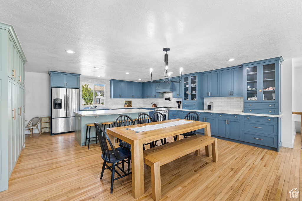 Dining space with light wood finished floors, a chandelier, recessed lighting, and a textured ceiling