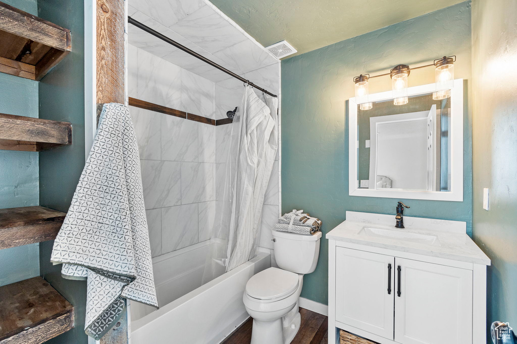 Bathroom with shower / bath combination with curtain, toilet, vanity, and wood finished floors