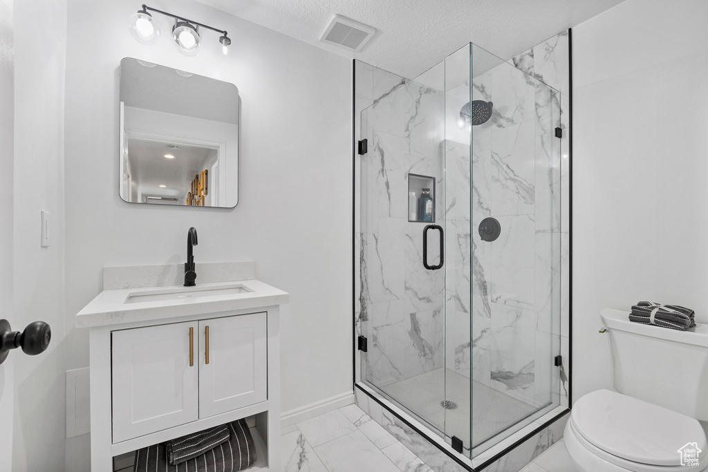 Full bath featuring marble finish floors, toilet, a marble finish shower, vanity, and baseboards